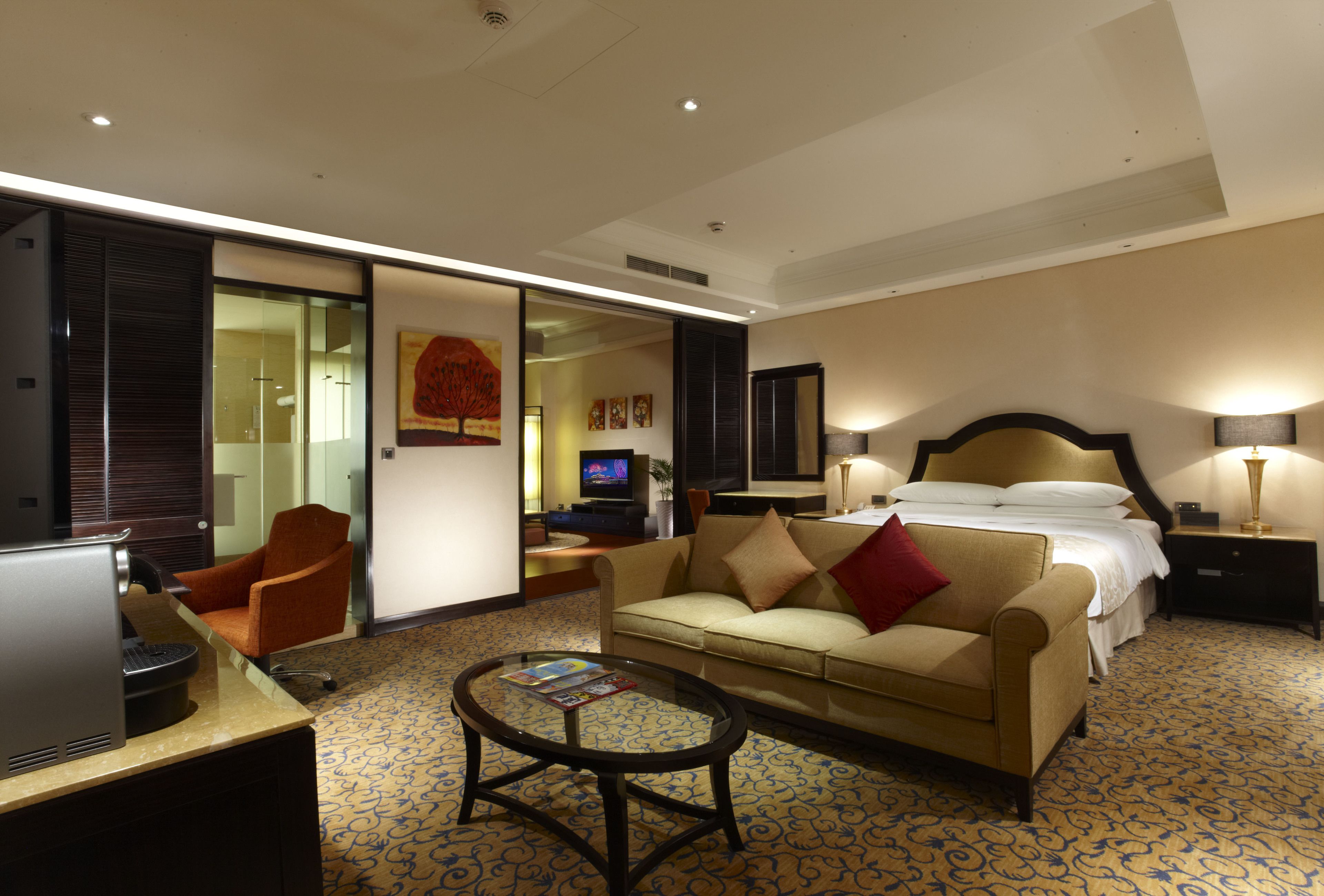 Een hotelkamer met een bank, een salontafel, een televisie, een bureau en een bed.