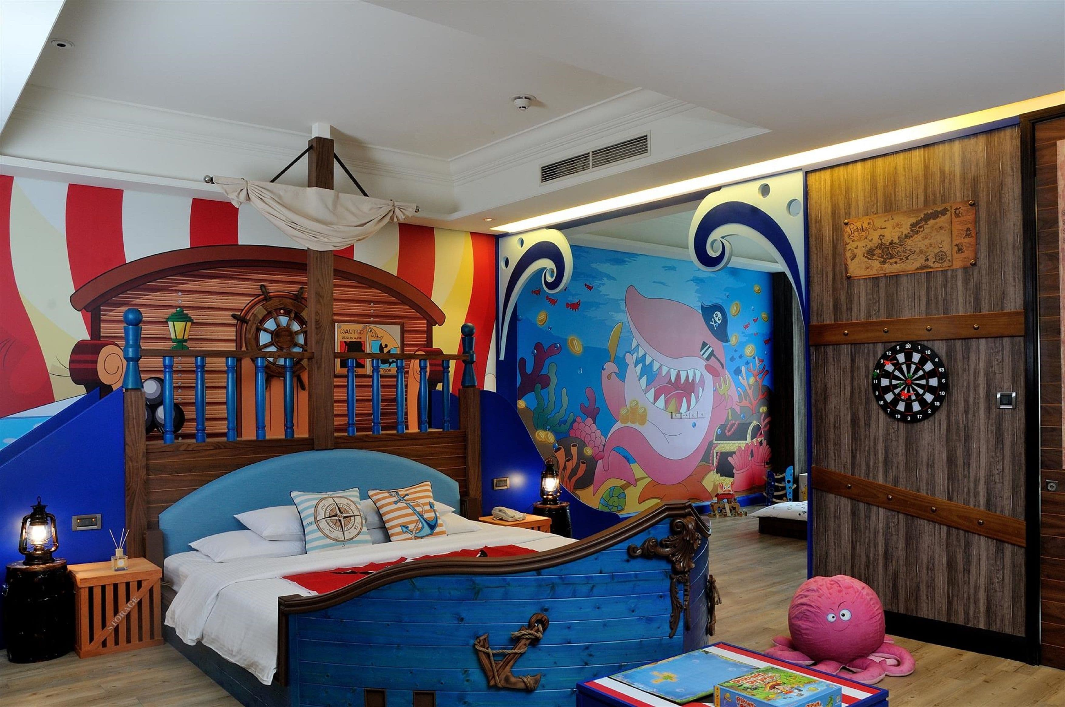 A child's bedroom with a bed, a wooden playhouse, a mural, and a dartboard.