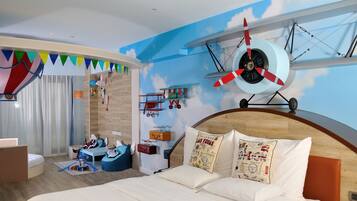 Un dormitorio con cama, cabecera de madera, mural de un avión y zona de juegos con juguetes.
