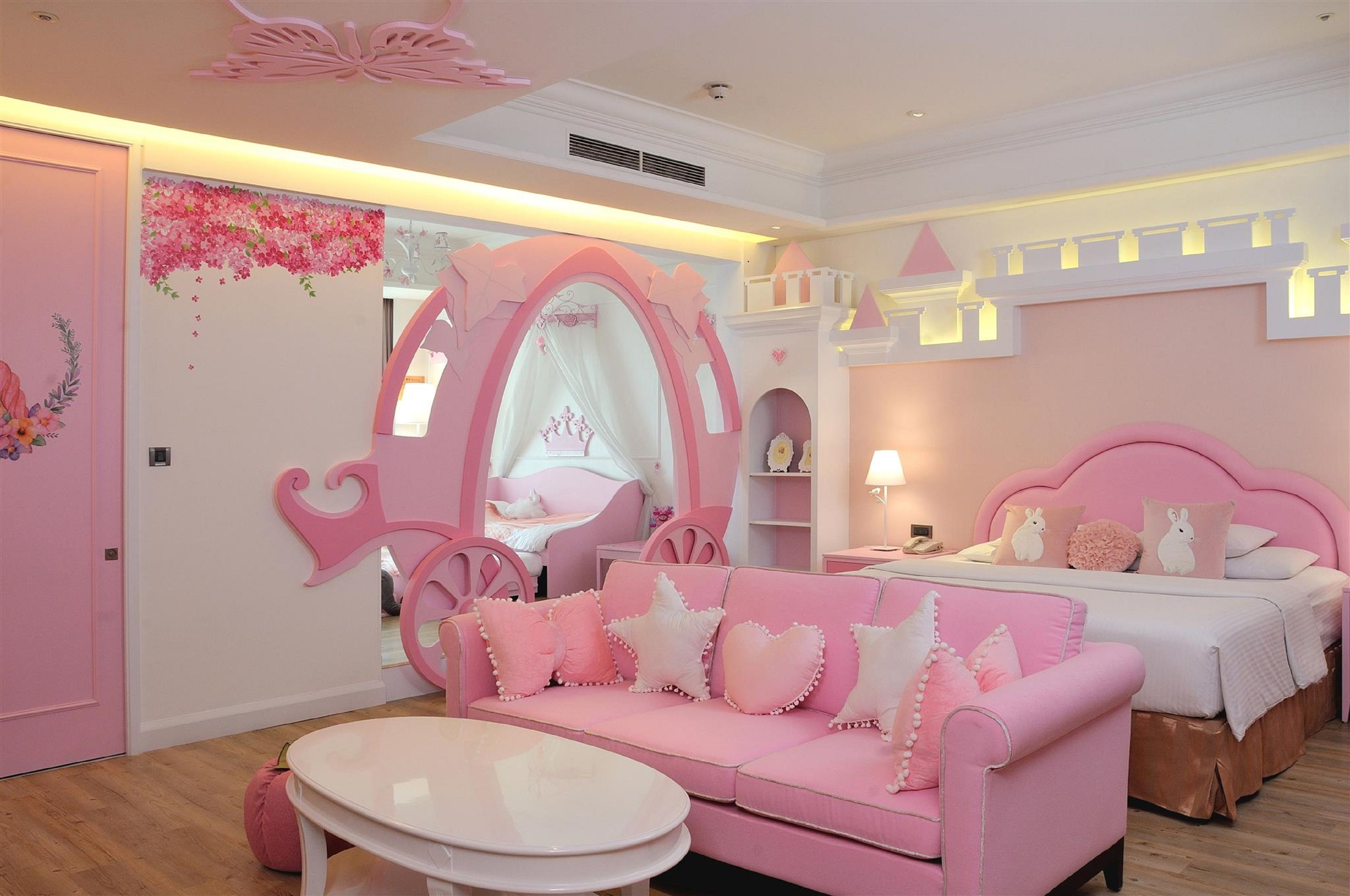 Ein zartrosa Zimmer mit Bett, rosa Sofa und kleinem Tisch.
