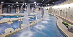 Una piscina interior moderna con múltiples juegos de agua y un diseño único.