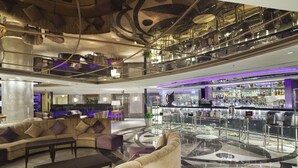 A spacious lobby with a curved sofa, a coffee table, and a bar area with a glass railing. - E-Da Royal Hotel (Kaohsiung)