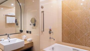 A modern bathroom with two sinks, a large mirror, a shower with grab bars, and a tiled wall.