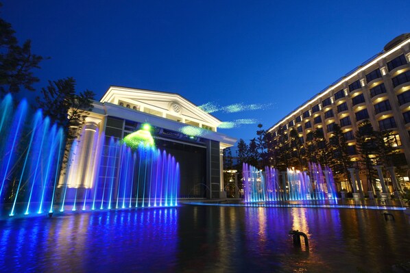 Un hotel con una gran fuente y una entrada bien iluminada.