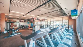 Une salle de sport équipée de tapis de course, de vélos d’exercice et d’autres appareils de musculation.