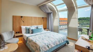 Une chambre d’hôtel dotée d’un grand lit, d’un coin salon, d’un balcon avec vue et d’un minibar.