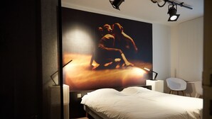 A modern hotel room with a large bed, a wall-mounted TV, a desk, and a chair. - Focus Hotel (Kortrijk)