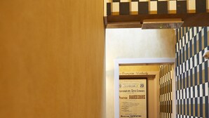 A staircase with a checkered wall pattern and a door with a sign. - Focus Hotel (Kortrijk)