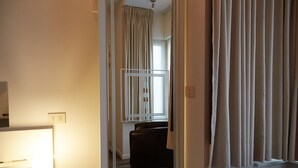 A hotel room with a bed, a desk, a chair, and a window with curtains. - Focus Hotel (Kortrijk)