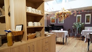 A cozy cafe with wooden furniture, a piano, and a variety of cups and mugs on display. - Focus Hotel (Kortrijk)