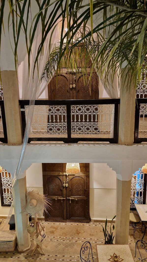 A traditional interior with a wooden door, decorative metalwork, and hanging plants.