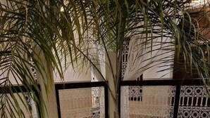 Une cour intérieure dotée d’une piscine, de palmiers et d’un espace détente avec des tables et des chaises.