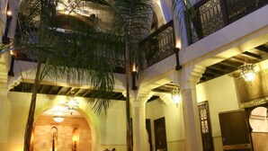 Un atrium à plusieurs niveaux, agrémenté d’arcades, de palmiers et de lustres suspendus.