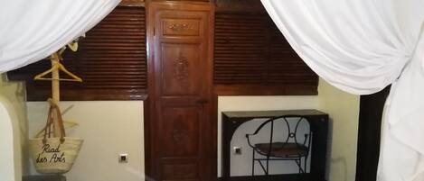 A room with a wooden door, a hanging chair, and a white fur rug.