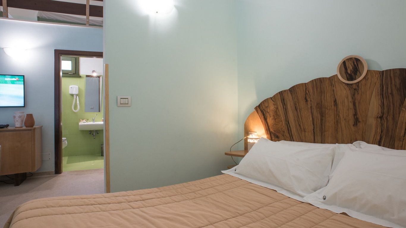 Een slaapkamer met een bed, een houten hoofdeinde, een nachtkastje en een televisie op een dressoir.