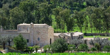 Un edificio de piedra con techo plano, rodeado de follaje y árboles.