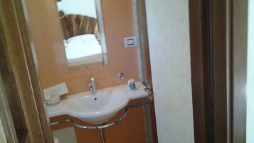 Une salle de bain avec un lavabo blanc, un miroir et un porte-serviettes.