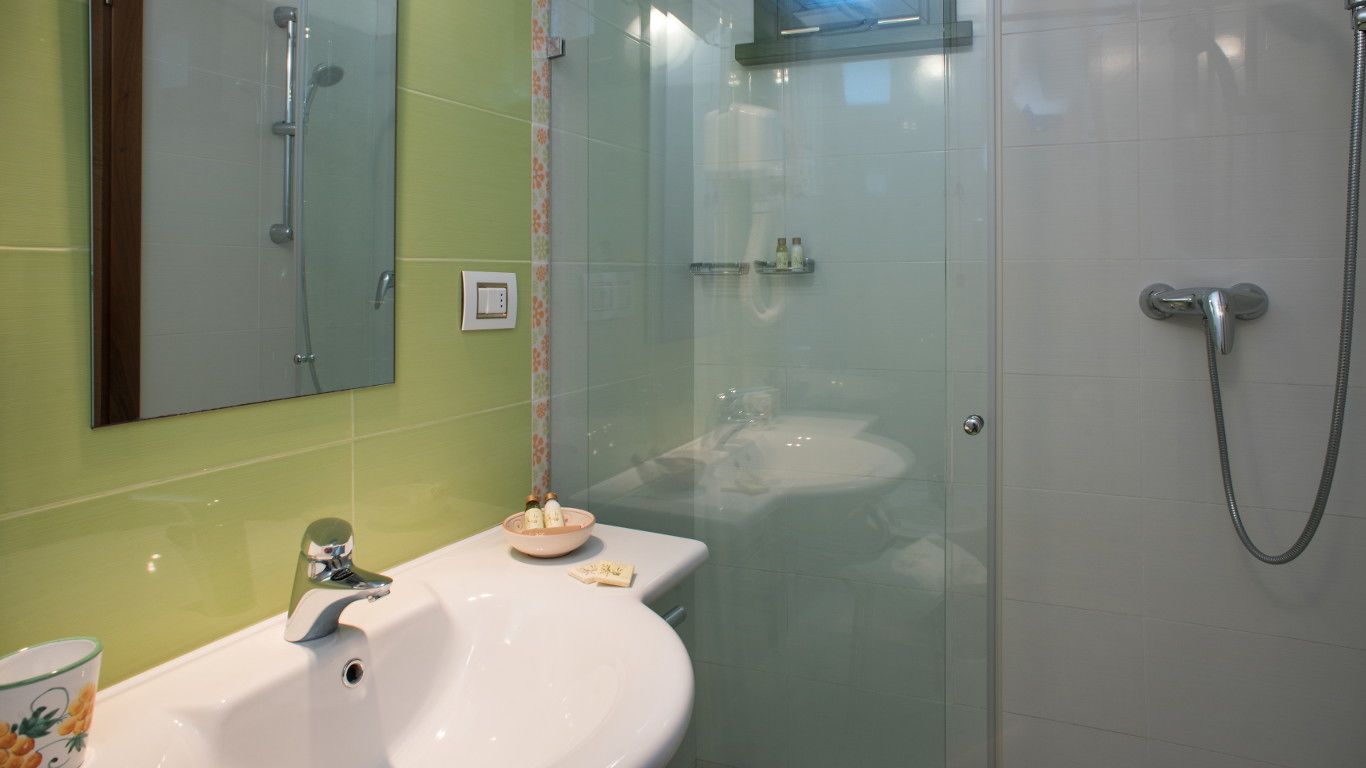A bathroom with a glass shower enclosure, a white sink, and a mirror above it.