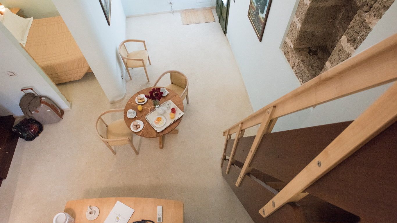 A dining area with a round table, four chairs, and a wooden staircase.