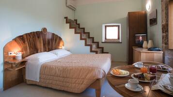 A hotel room with a bed, a dining table with breakfast, a TV, and a staircase.