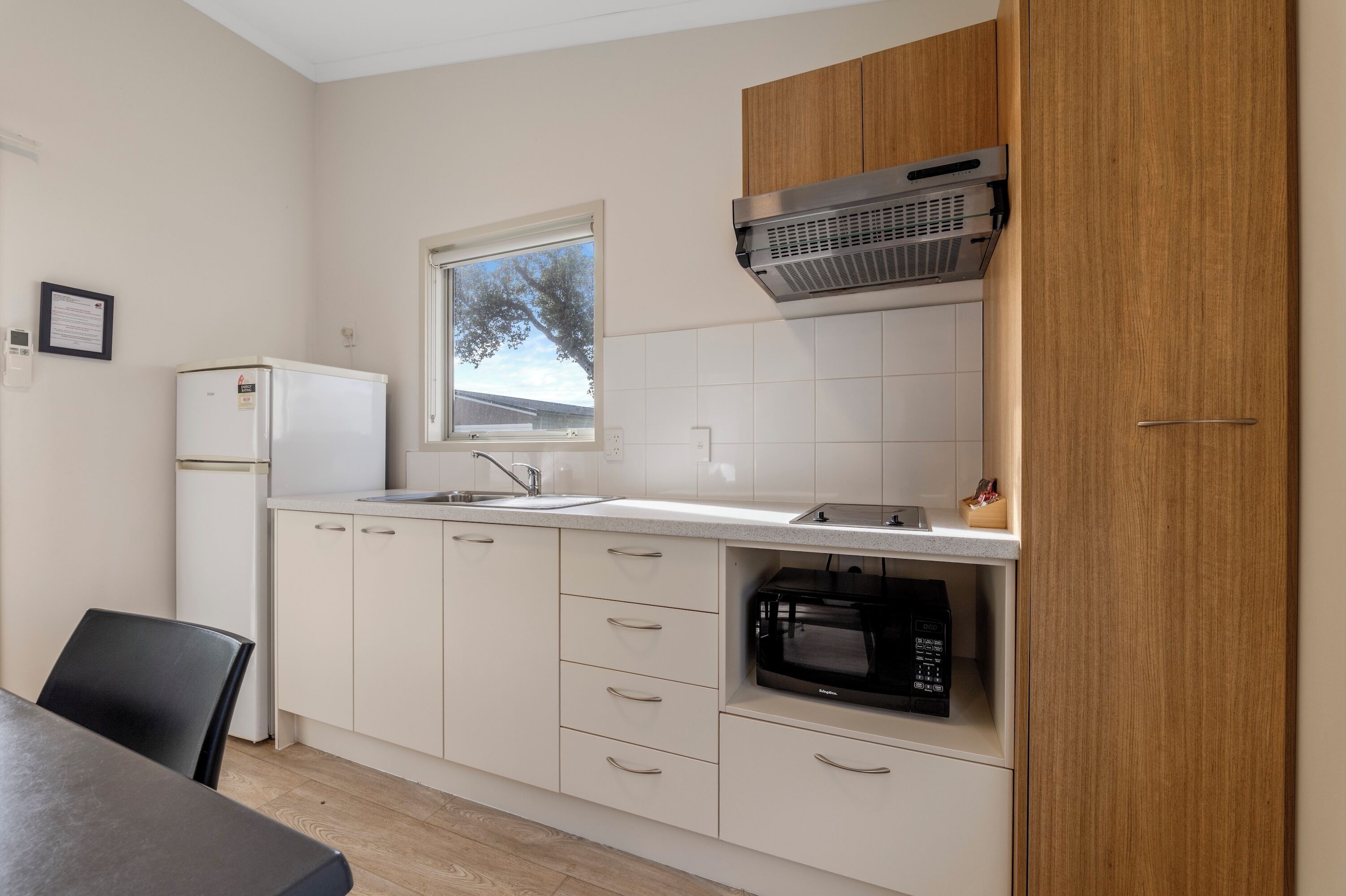 A compact kitchen with white cabinets, a built-in microwave, and a window above the sink.