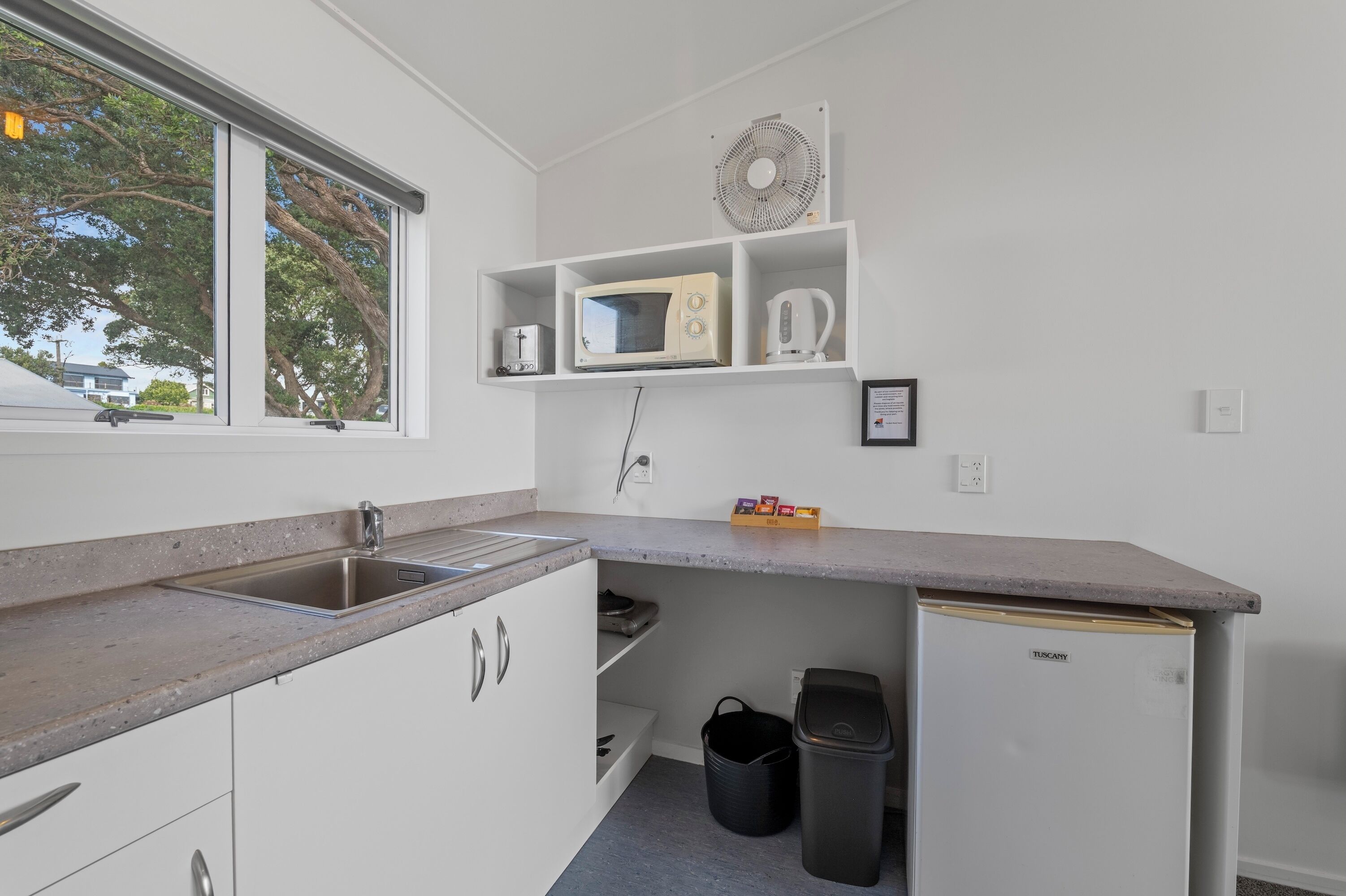 A compact kitchen with a built-in sink, a microwave, and a small refrigerator.