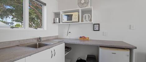 A compact kitchen with a built-in sink, a microwave, and a small refrigerator.