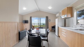 Une cuisine moderne avec un coin repas, des meubles en bois et une grande fenêtre donnant sur l’extérieur.