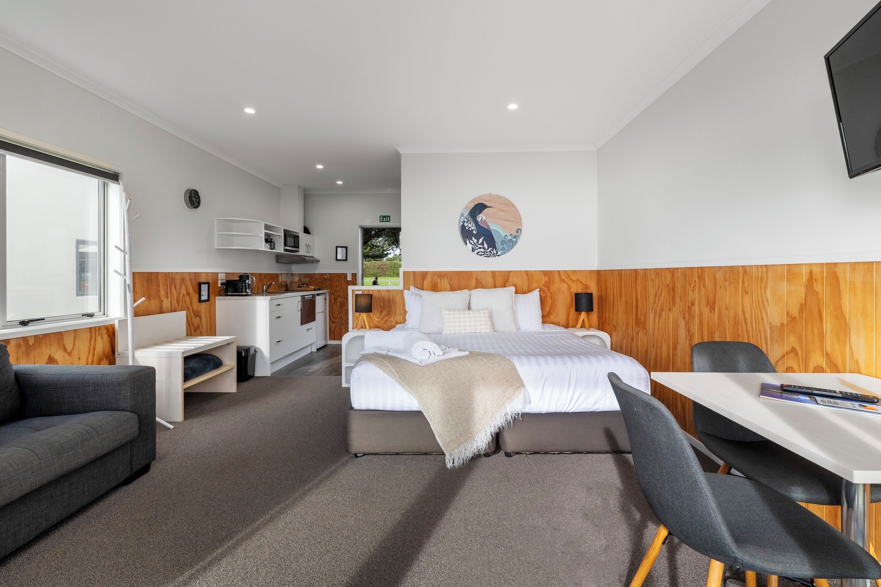 Una camera d'albergo moderna con un letto, una scrivania, una sedia, un divano e una televisione.