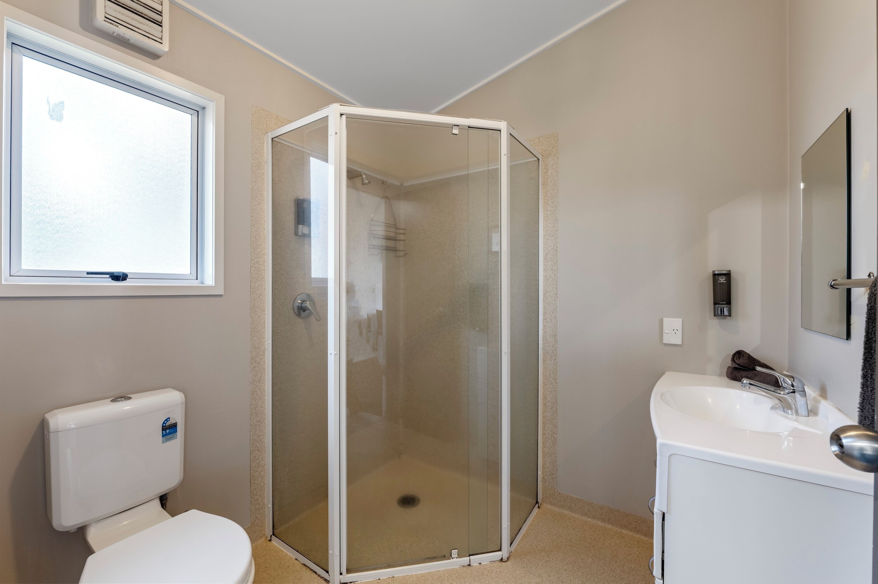 A bathroom with a glass-enclosed shower, a toilet, and a sink.