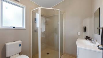 A bathroom with a glass-enclosed shower, a toilet, and a sink.