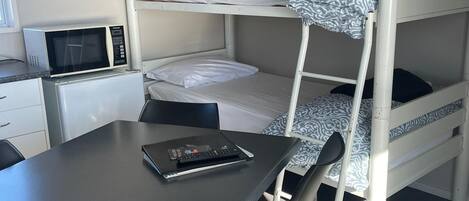 A bunk bed room with a desk, chair, and microwave.