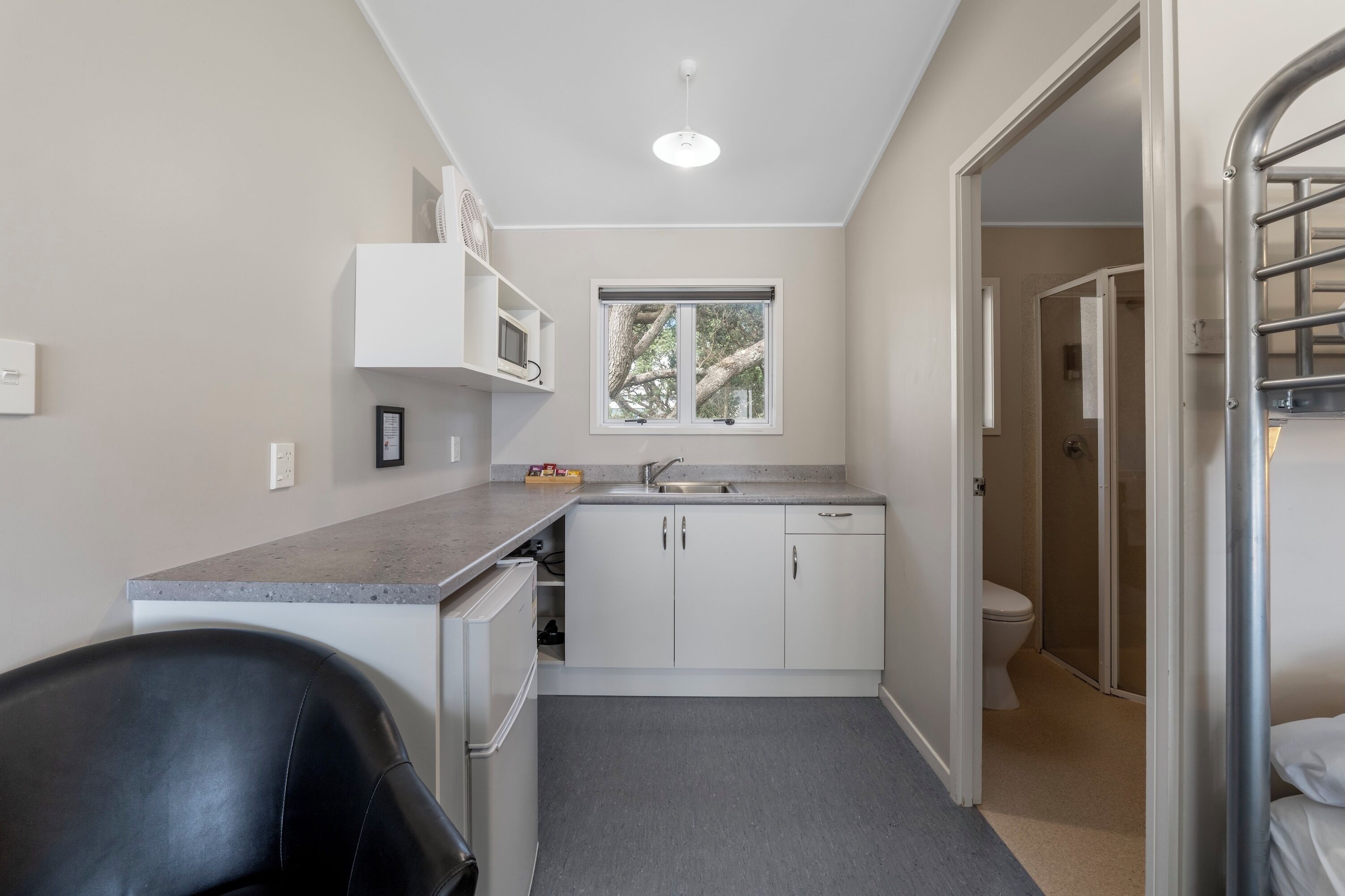 A compact kitchen with a microwave, sink, and cabinets.