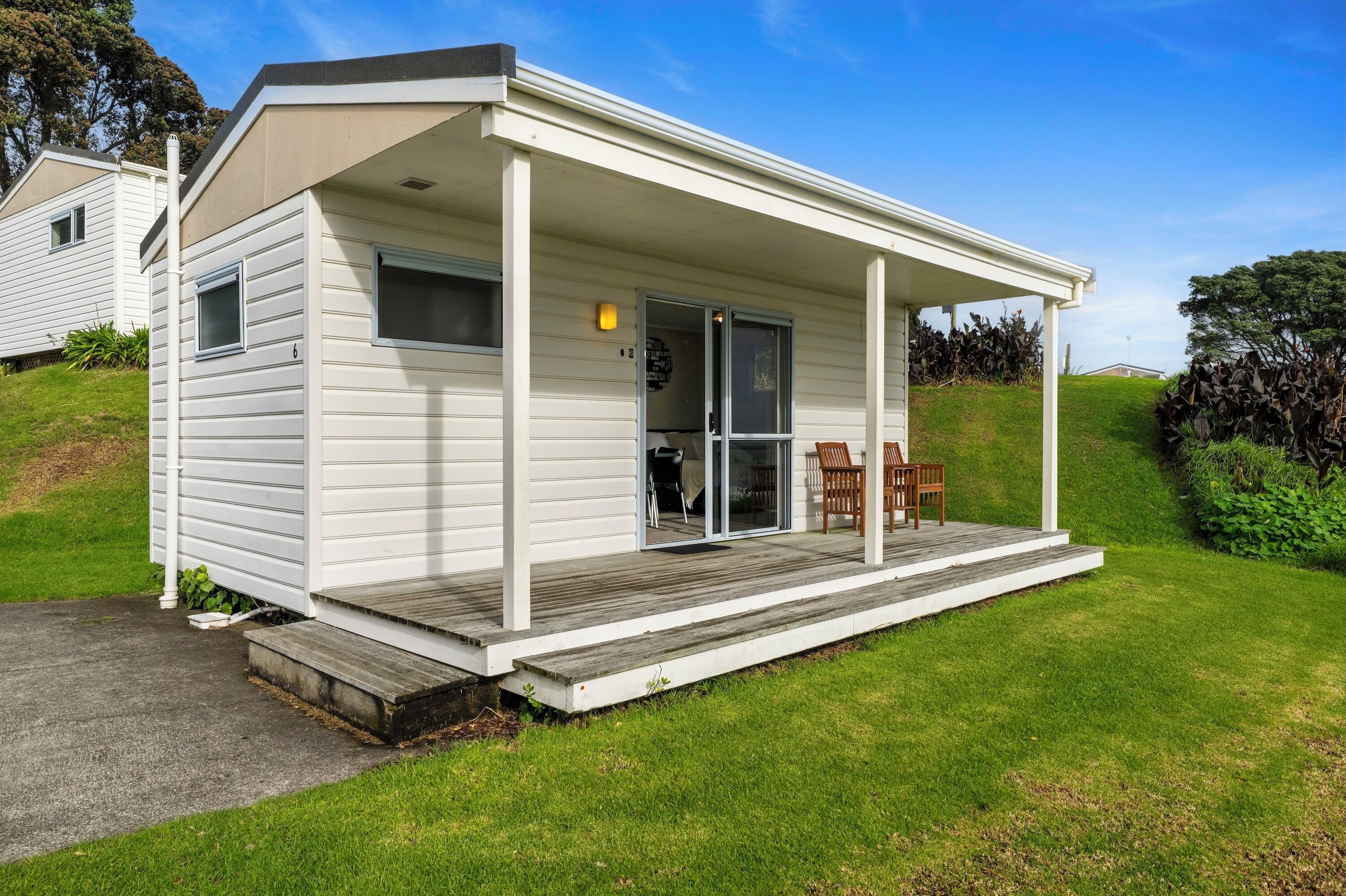 A single-story mobile home with a covered porch and a sliding glass door entrance.