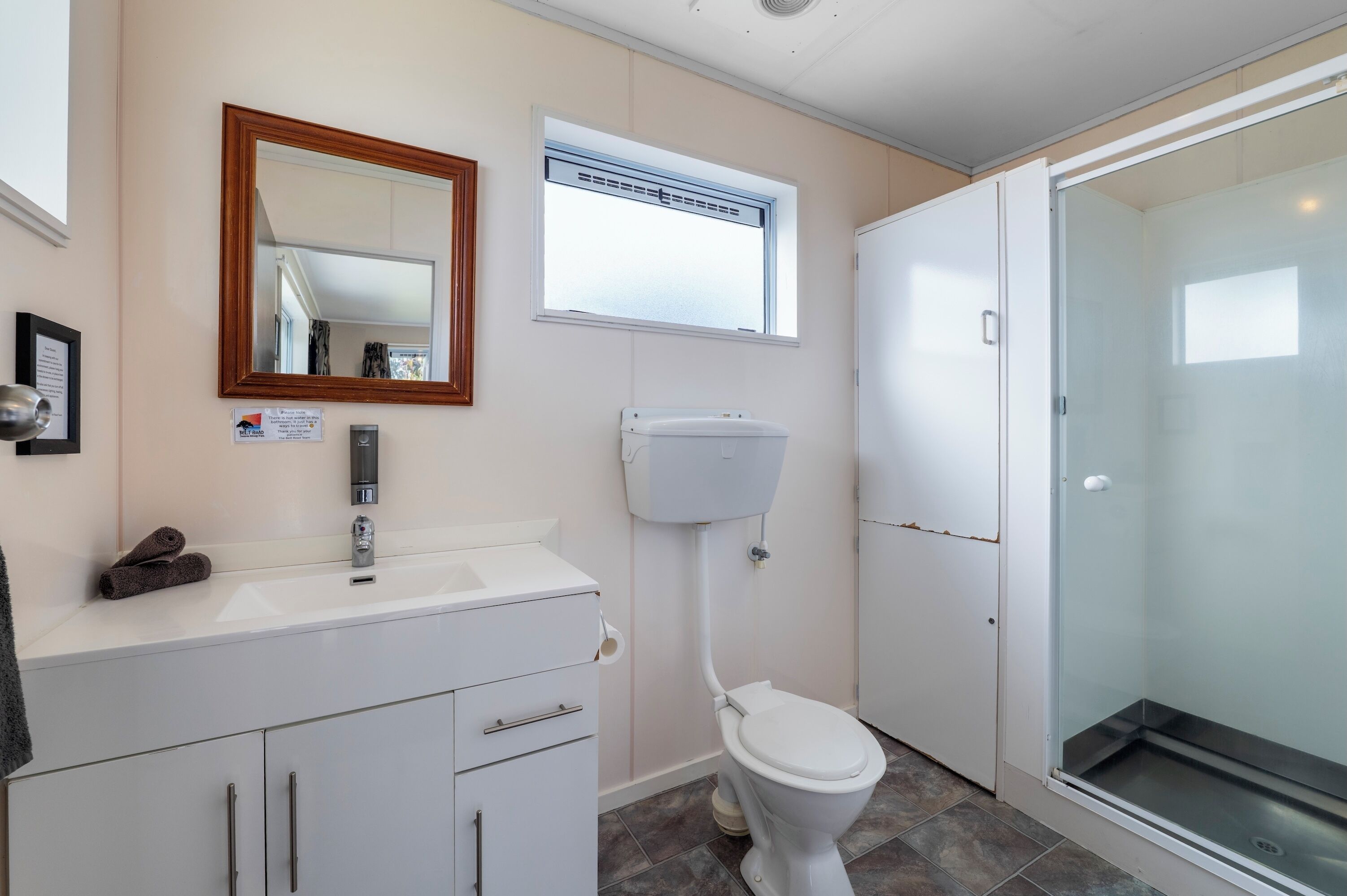 Een moderne badkamer met een wit wastafel, toilet en douche.