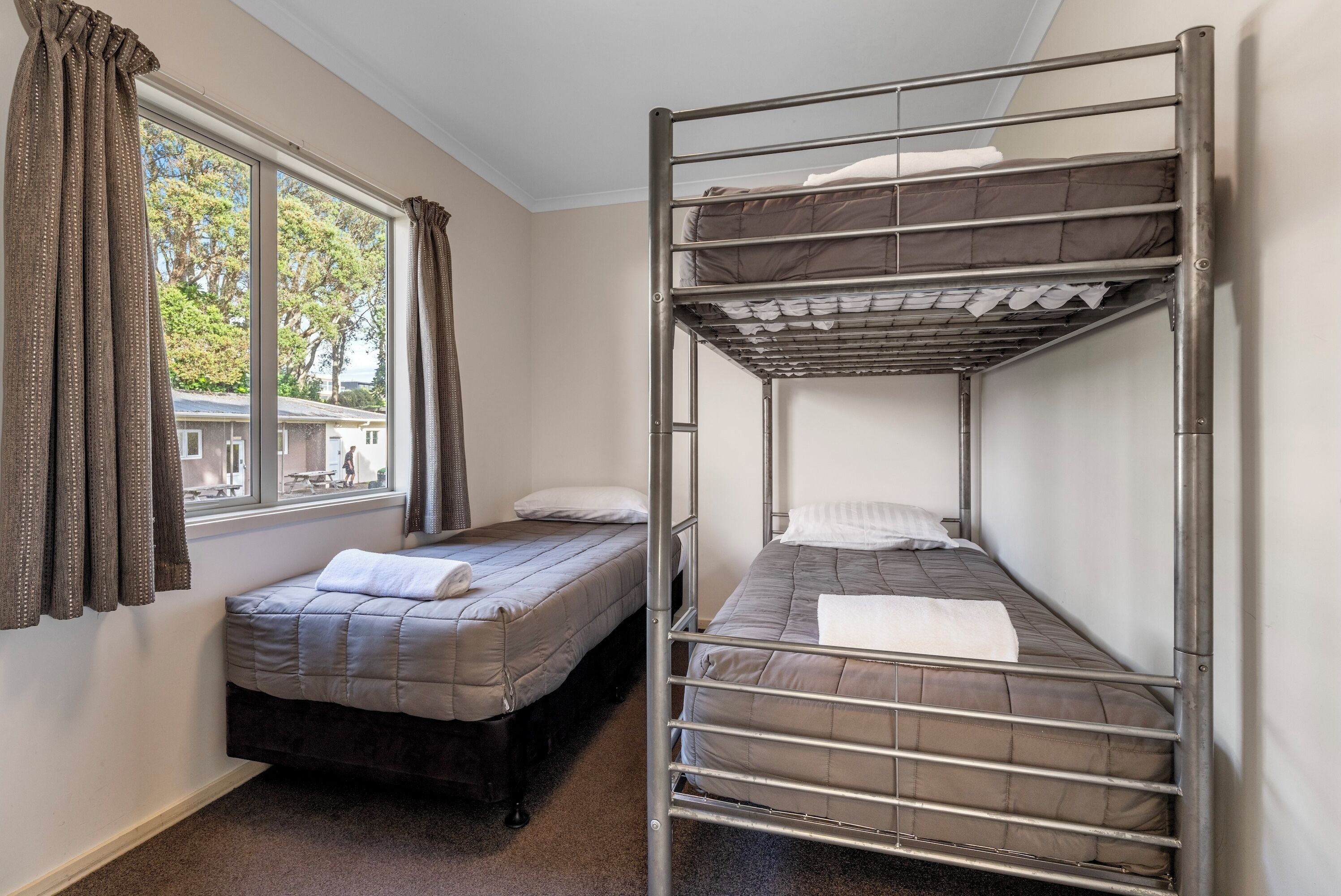 Un dormitorio con literas, una ventana con cortinas y vista a un edificio.