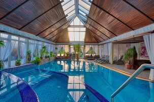 Una piscina techada, una piscina al aire libre de temporada, sombrillas