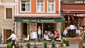 A building with a sign reading "Nobel Hostel" and a cafe named "SOFA CAFE & RESTAURANT" with outdoor seating. - Nobel Hostel Guesthouse (Istanbul)