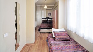 A narrow hallway leading to a bedroom with two beds, a wardrobe, and a hanging light fixture. - Nobel Hostel Guesthouse (Istanbul)