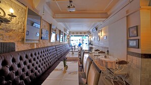A long, plush, leather-lined booth with a white tablecloth and a vase of flowers. - Nobel Hostel Guesthouse (Istanbul)