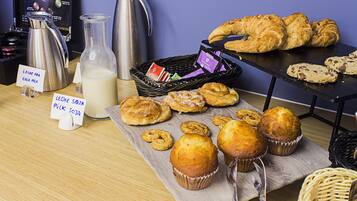 Un bufé de desayuno con bollería, muffins y bebidas.