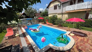 A swimming pool with inflatable toys, sun loungers, and a covered area with umbrellas. - Joker Villa Apartementhaus (Hévíz)