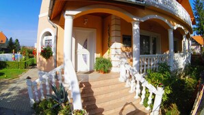 A two-story building with a balcony, a staircase, and a garden area.