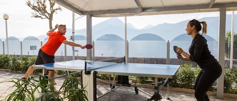 Een tafeltennistafel buiten opgesteld, met een schilderachtig meer en bergen op de achtergrond.
