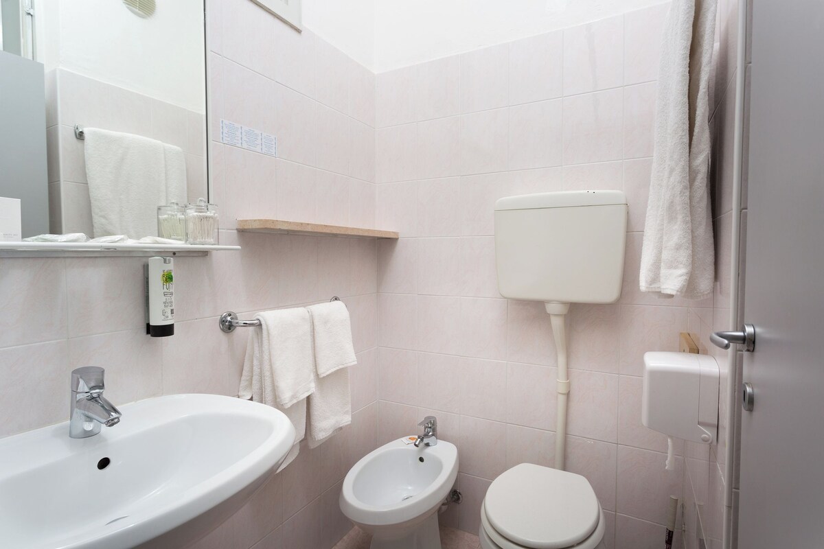 Un baño con lavamanos, bidé, inodoro y un perchero para toallas.