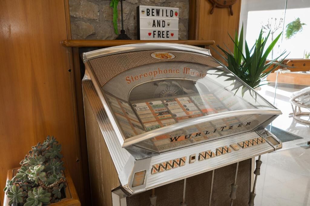 Un lettore stereofonico vintage con un coperchio trasparente, posizionato su un piano di legno.