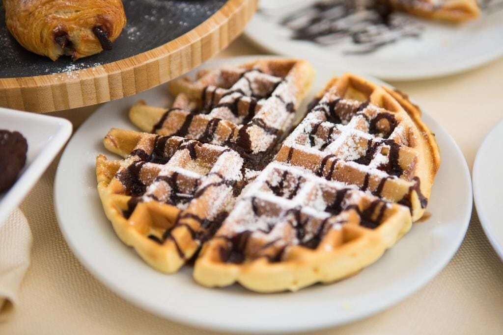 Un plato de waffles con cobertura de chocolate y azúcar glas.