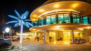 A hotel with a curved exterior, a palm tree decoration, and a bike rack. - Hotel Caribe by Double Hospitality (Brenzone sul Garda)