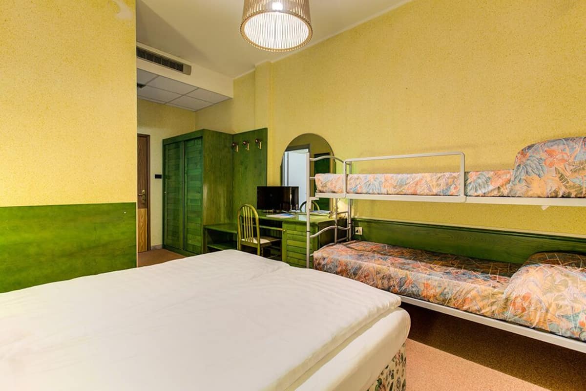 A room with a bunk bed, a desk with a chair, and a wardrobe.