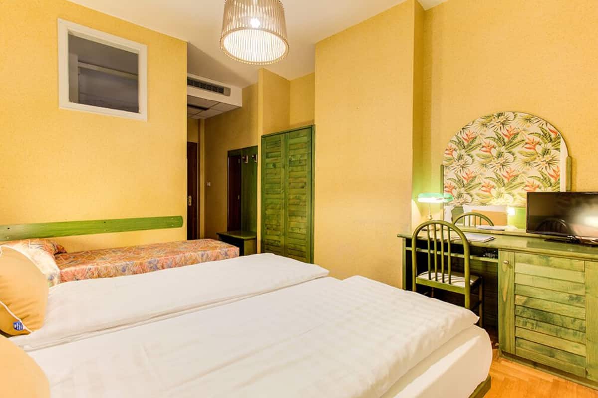 A room with two beds, a desk with a chair, a television, and a decorative wall piece.